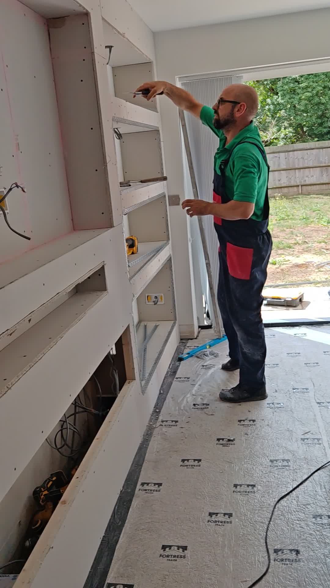 Built.Calm fixing plasterboard shelving into a media wall frame