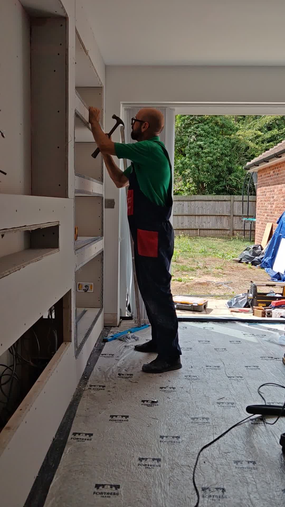 Built.Calm hand-finishing shelving inside a media wall frame