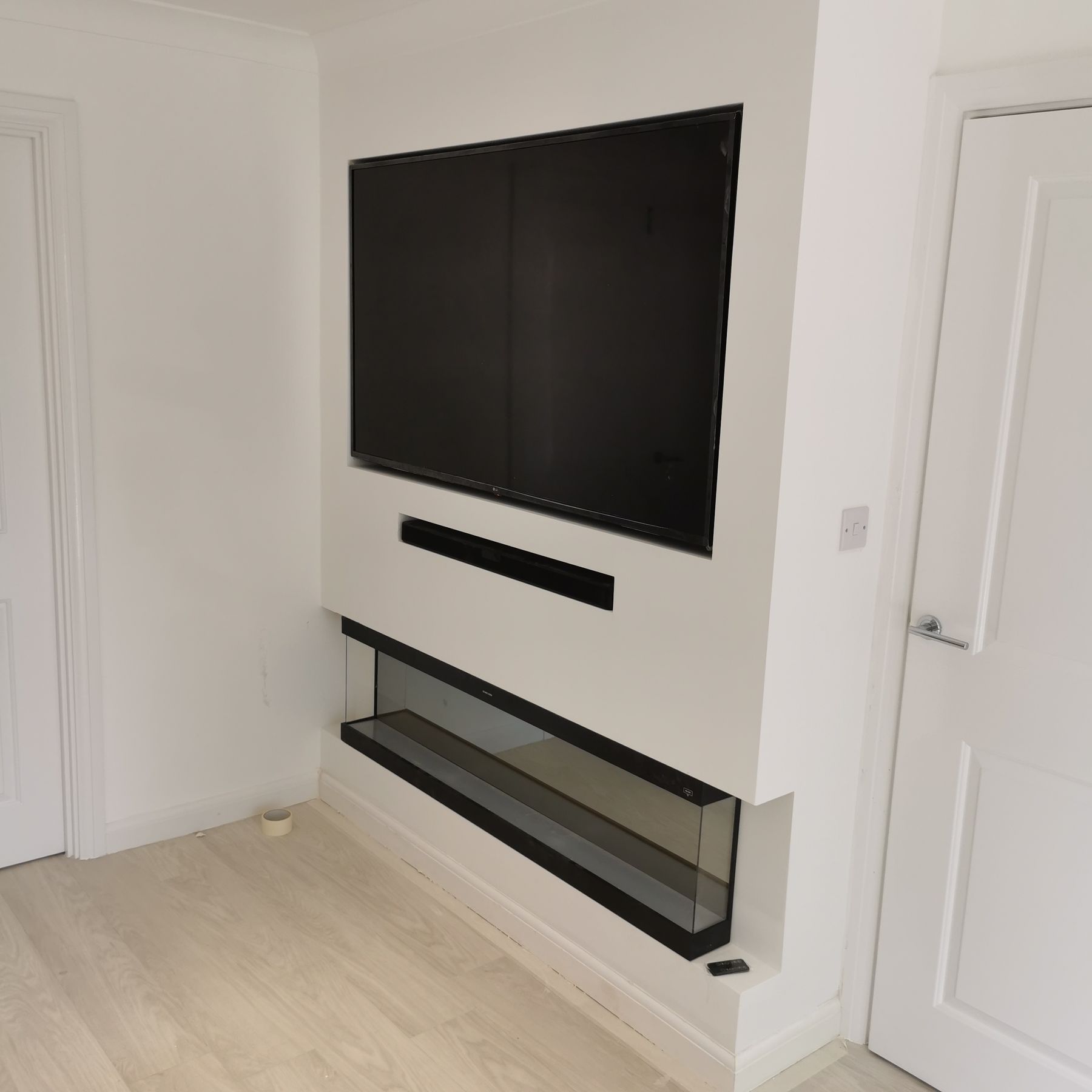 Freestanding chimney-breast style media wall with recessed TV and glass-fronted fire